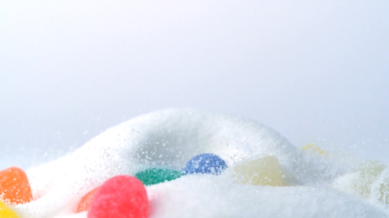 Colorful candy surrounded by sugar, representing the impact of sugar on collagen and skin aging