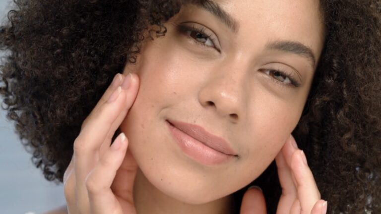 A woman gently touching her face, showing a calm expression, with healthy skin as she reflects on skin aging