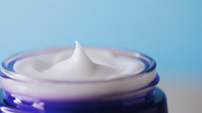 A close-up of an open skincare cream jar showing the texture of the product inside