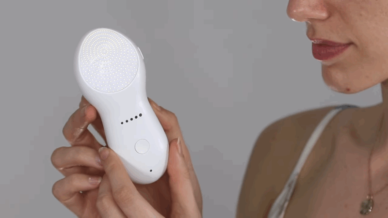 A woman holds a handheld radiofrequency device before starting a skin tightening treatment on her face