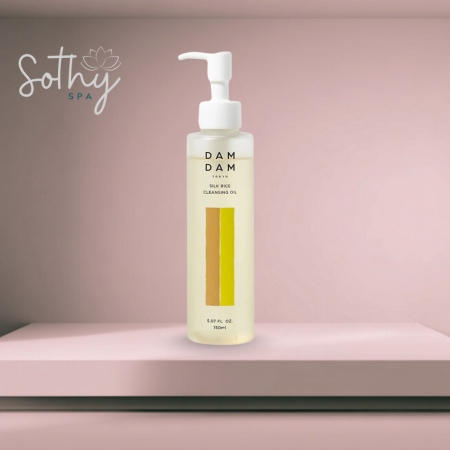 Clear bottle of Damdam Silk Rice Cleansing Oil with a pump dispenser, shown on a pink spa shelf background