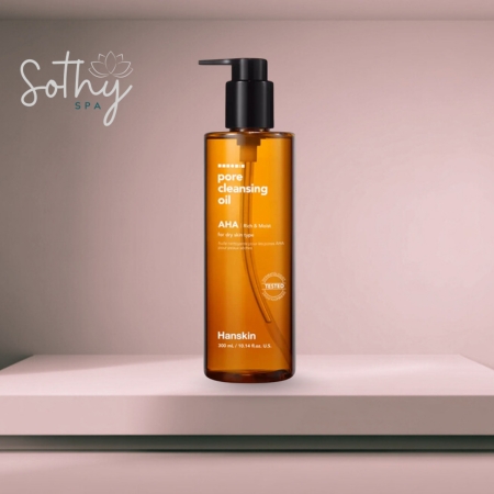 Amber bottle of Hanskin Pore Cleansing Oil with black pump, placed on a pink spa-themed background shelf