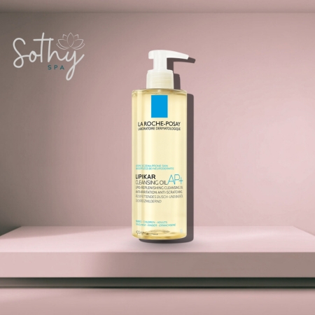 Bottle of La Roche-Posay Lipikar AP+ Gentle Cleansing Oil with a pump dispenser, placed against a soft pink spa-themed background