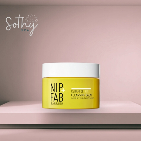 Yellow jar of Nip + Fab Ceramide Fix Cleansing Balm with white lid, displayed on a pink spa shelf background