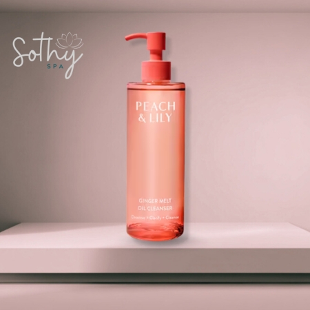 Bottle of Peach & Lily Ginger Melt Oil Cleanser in a coral-pink pump bottle displayed on a soft pink background with spa branding