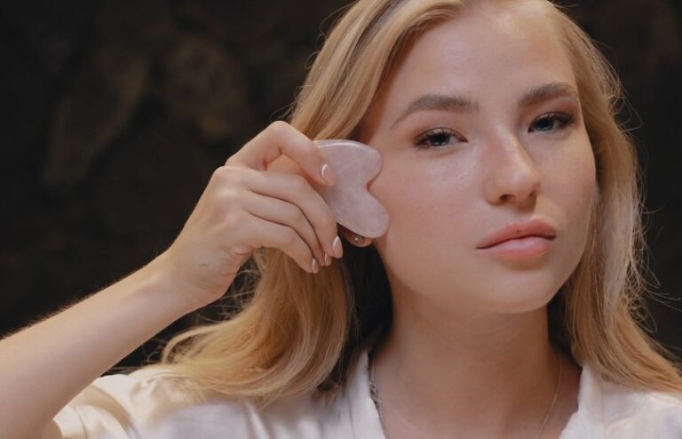 A woman is applying a face mask, focusing on her skincare routine in a well-lit bathroom