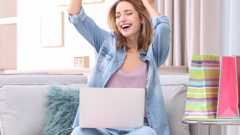 A happy woman with a laptop and shopping bags shows how the right tech stack supports e-commerce loyalty