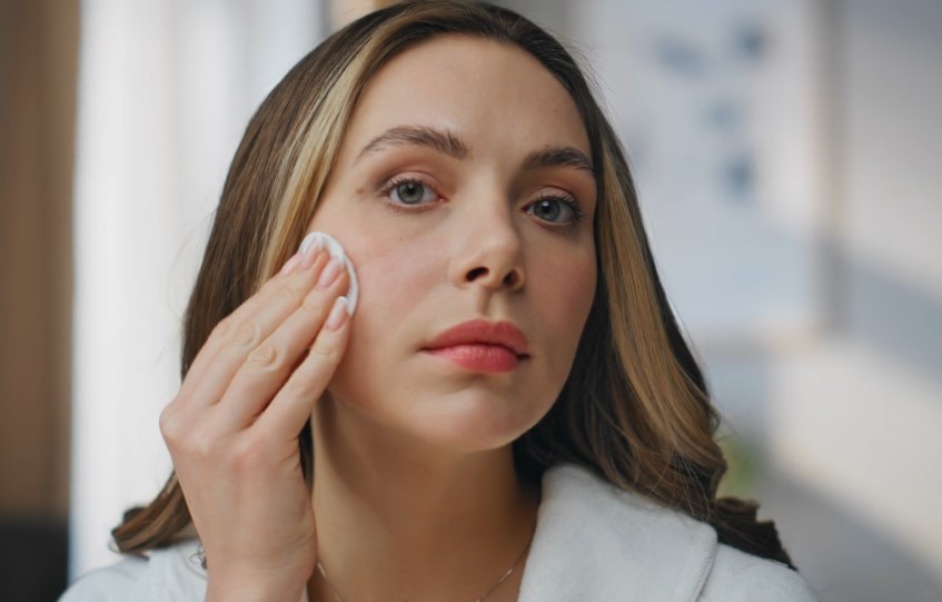 A woman cleans her face with a facial wipe