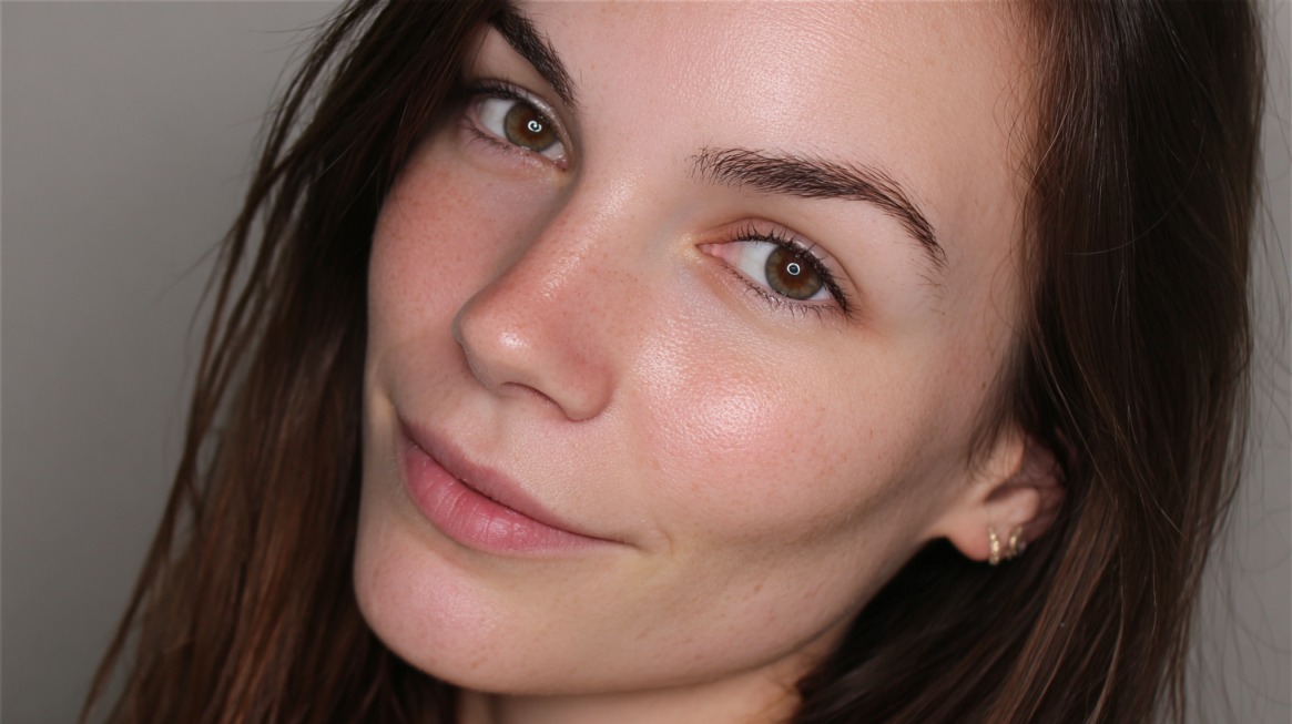 Close-up of a woman with clear, glowing skin, minimal makeup, and a hydrated look