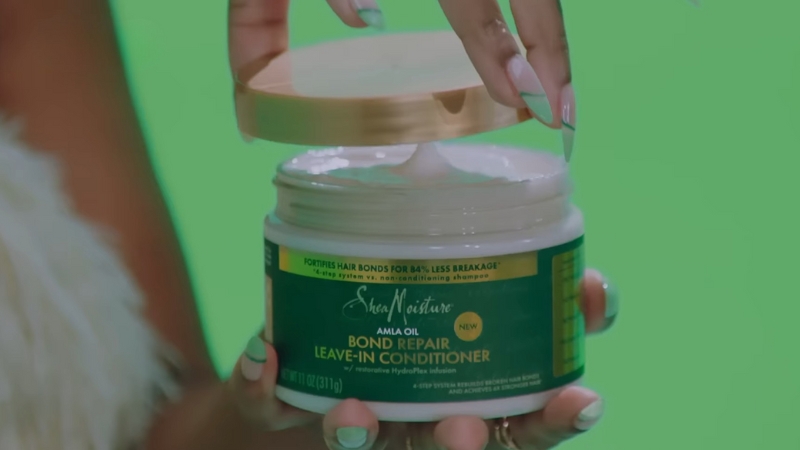 A person opens a jar of Shea Moisture Bond Repair Leave-In Conditioner