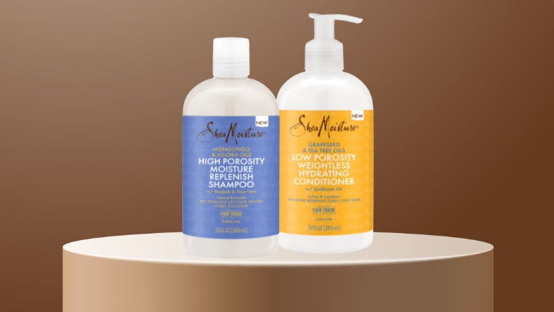 Two Shea Moisture hair care bottles, a shampoo and conditioner, are displayed on a round stand against a brown background