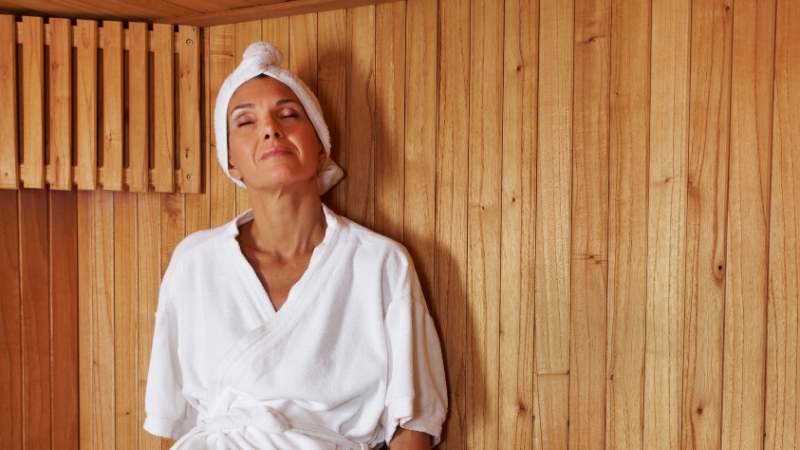 Woman in a white robe relaxing in a sauna during a spa day after a facial treatment